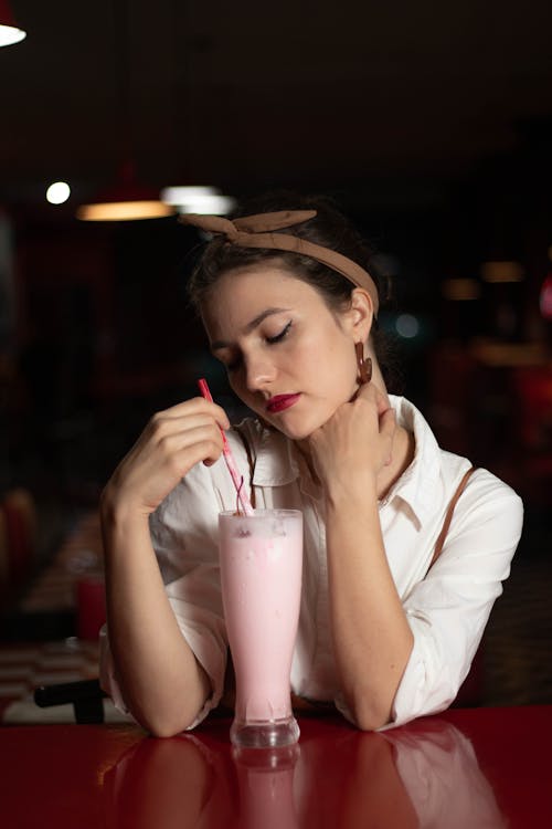 Woman Closes Her Eyes and Holds a Red Drinking Straw 