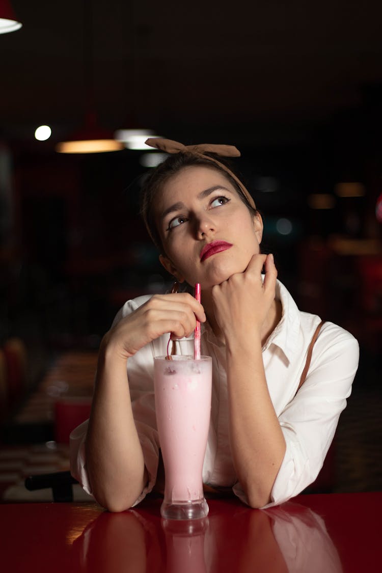 A Thinking Woman With A Glass Of Pink Smoothie