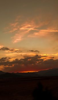 A breathtaking sunset with dramatic clouds over a silhouetted mountain range.