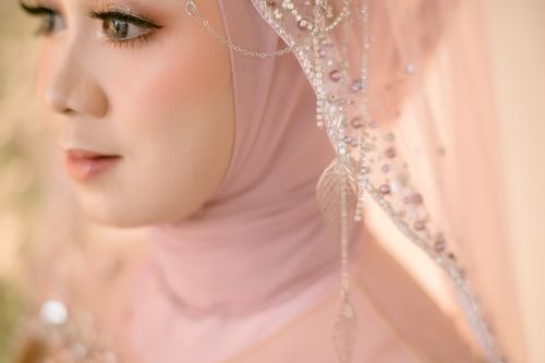 Free Close-up portrait of a woman wearing a beautifully adorned hijab, showcasing intricate fabric and delicate makeup. Stock Photo