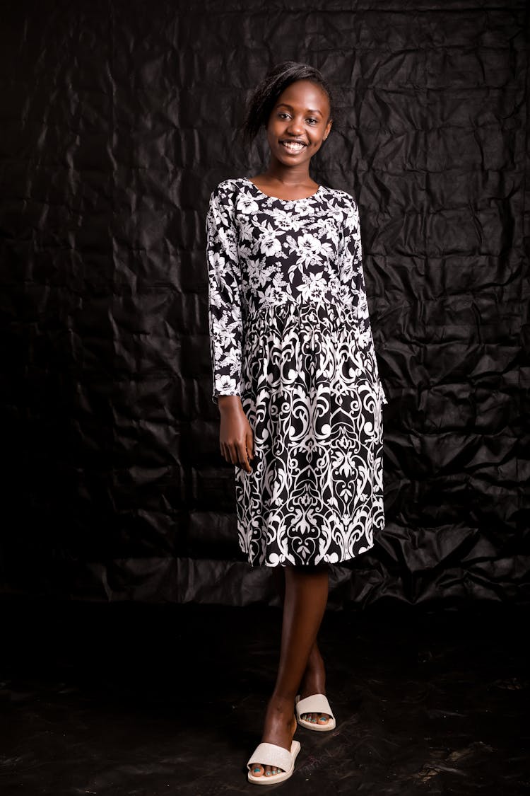 A Woman In Black And White Floral Dress And White Slippers