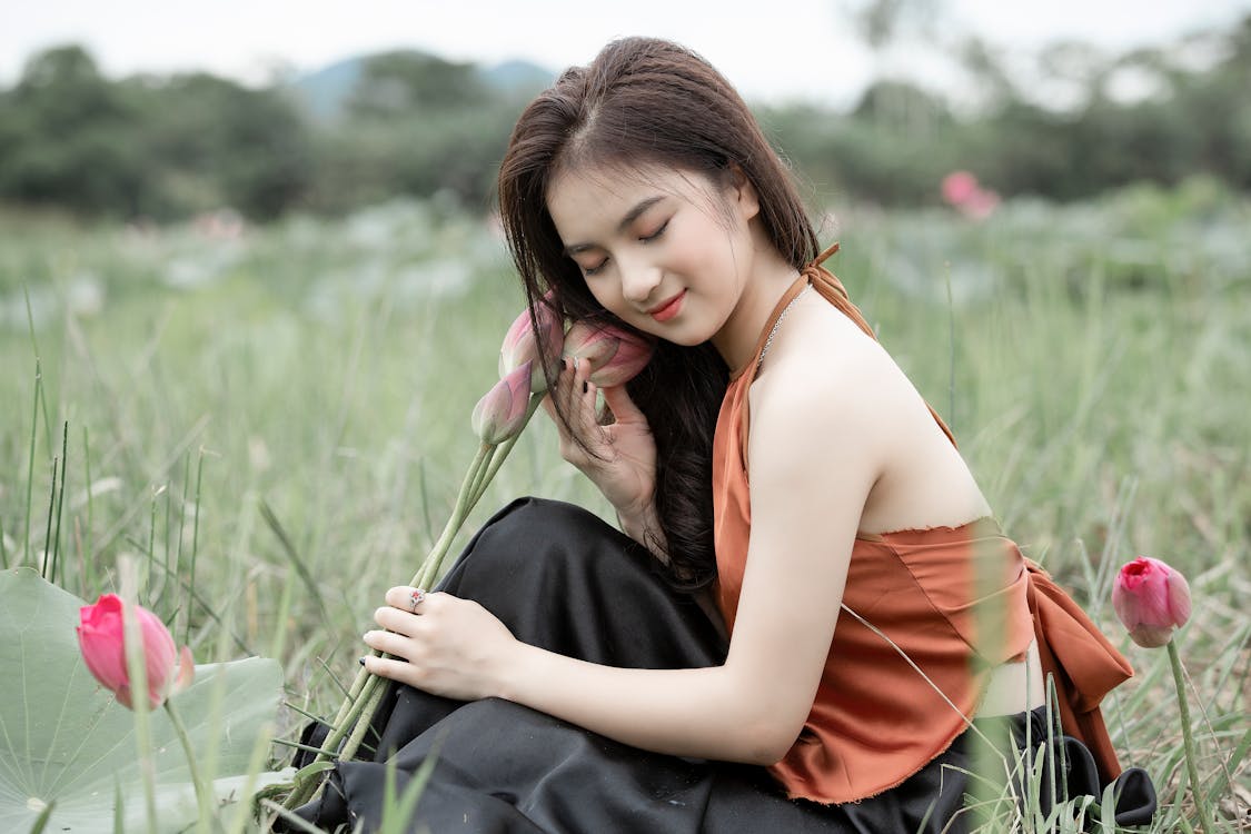 Woman Holding Flowers While Sitting