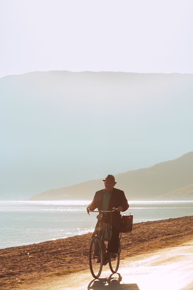 Man Cycling Along River In Mountains