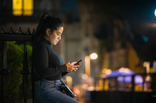 Free A woman is engrossed in her smartphone on a bustling street in Mexico City at night. Stock Photo