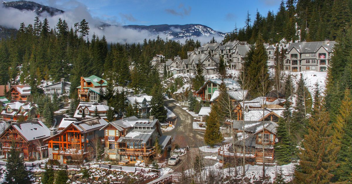 Charming snowy village with coniferous trees in Whistler, BC, under blue skies.