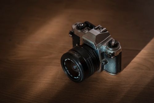 Free A classic Nikon camera placed on a wooden surface, captured in warm soft light. Stock Photo