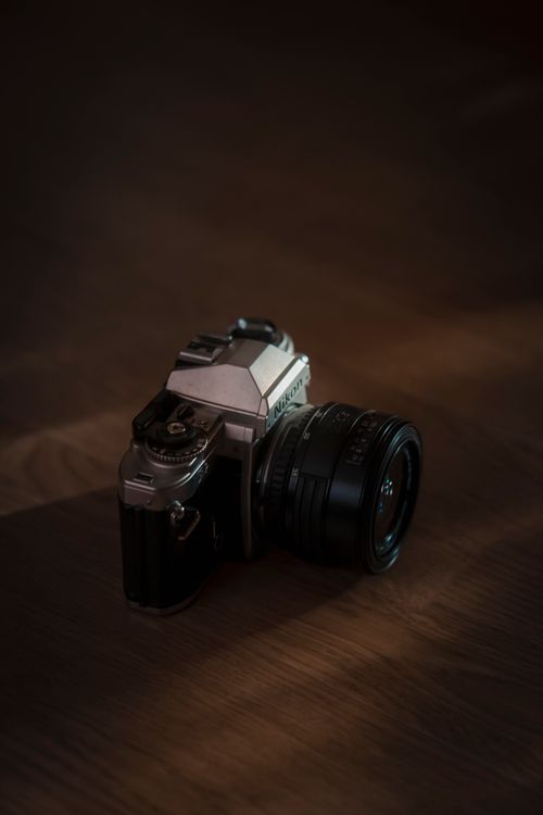 Free Close-up view of a vintage camera on a wooden surface, highlighted by subtle lighting. Stock Photo