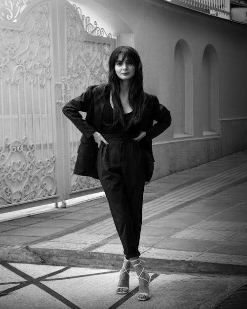 Woman in Blazer and Pants Standing Near a Metal Gate