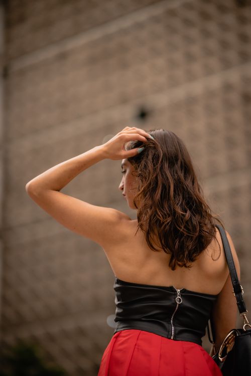 Free Stylish woman with long hair in a cityscape, showcasing elegant fashion from behind. Stock Photo