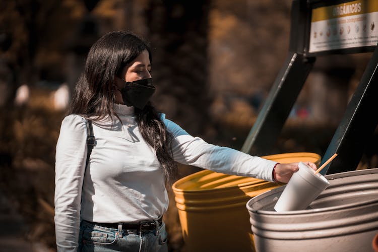 Woman Throwing Plastic Cup In Trash Bin