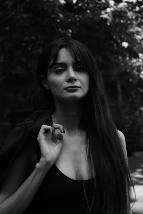 A Grayscale of a Woman in a Tank Top Holding a Blazer