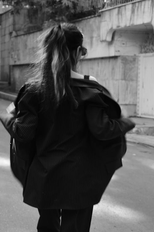 A Grayscale of a Woman Removing Her Blazer