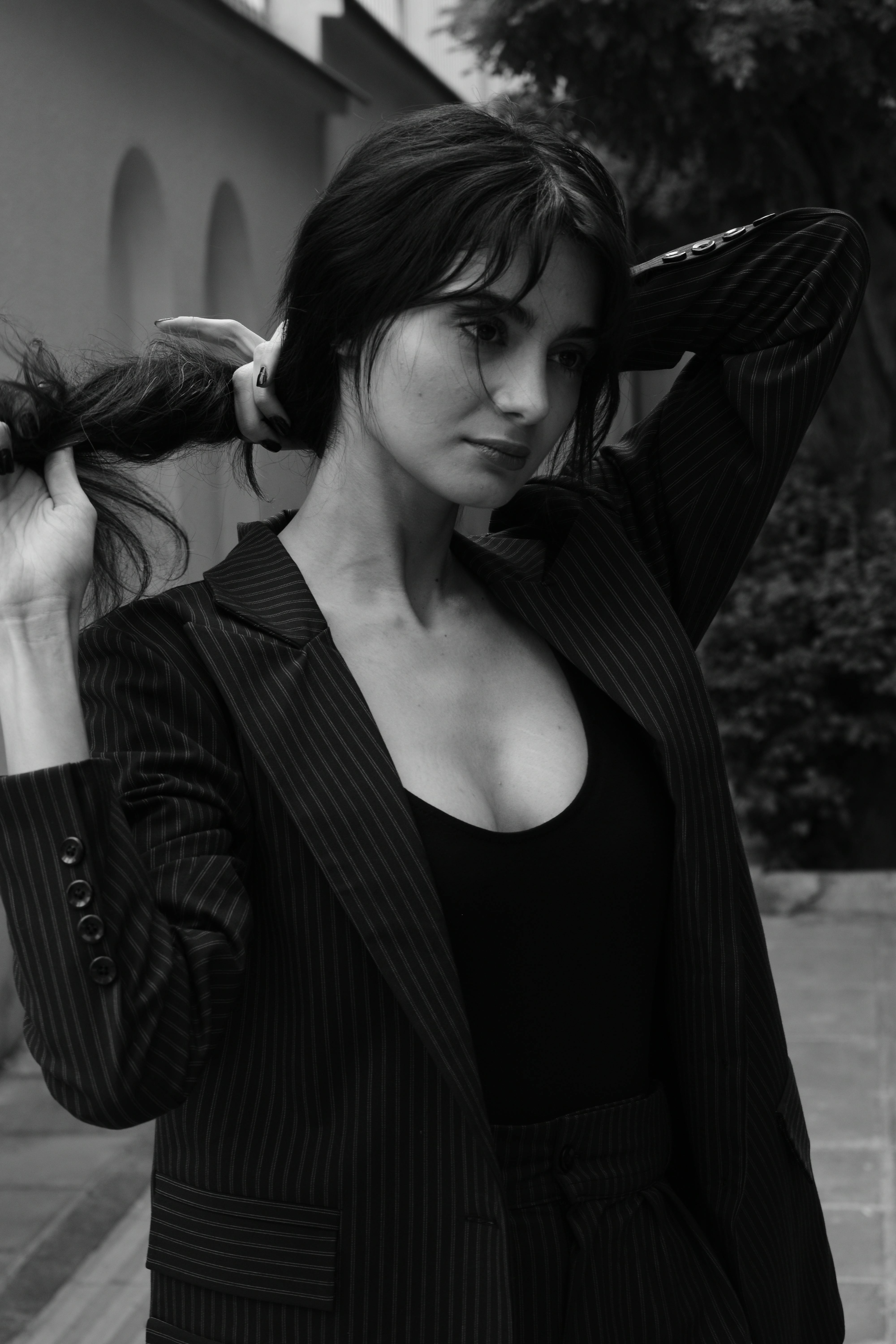 Stylish woman in striped blazer creating a classic monochrome portrait outdoors.