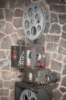 Classic vintage film projector displayed against a rustic stone wall.