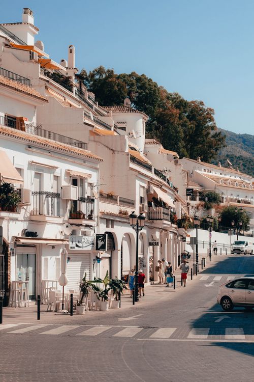 Free Picturesque street scene in Spain with white buildings, people strolling under a blue sky. Stock Photo