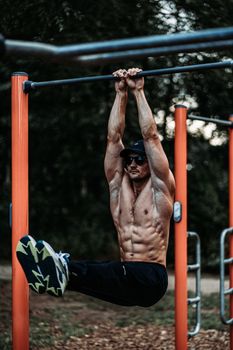 An athletic man exercising on a horizontal bar outdoors, showcasing strength and fitness.