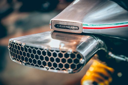 特写展示了一款带有意大利国旗装饰带的现代摩托车排气装置，其复杂的工程与设计清晰可见