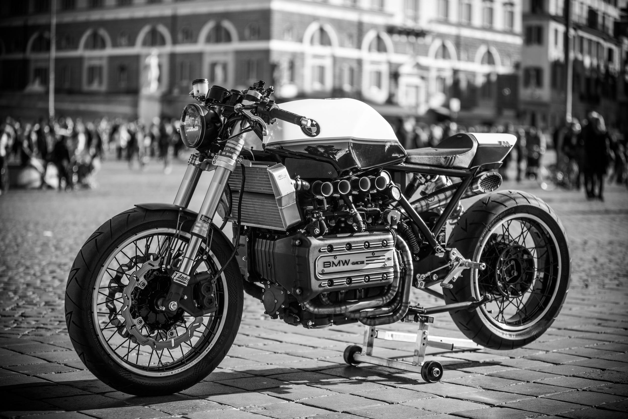 A vintage BMW motorcycle on display in a bustling Roman plaza, capturing timeless style.