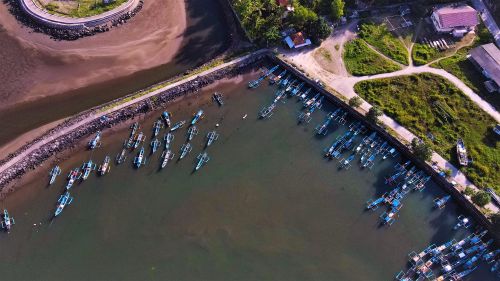 Free Aerial shot of docked fishing boats in Pangandaran, Indonesia, showcasing vibrant coastal scenery. Stock Photo
