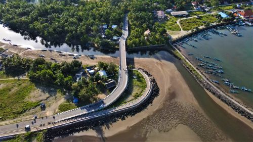 Free Aerial view of a winding bridge over lush greenery and waterways in Pangandaran, Indonesia. Stock Photo