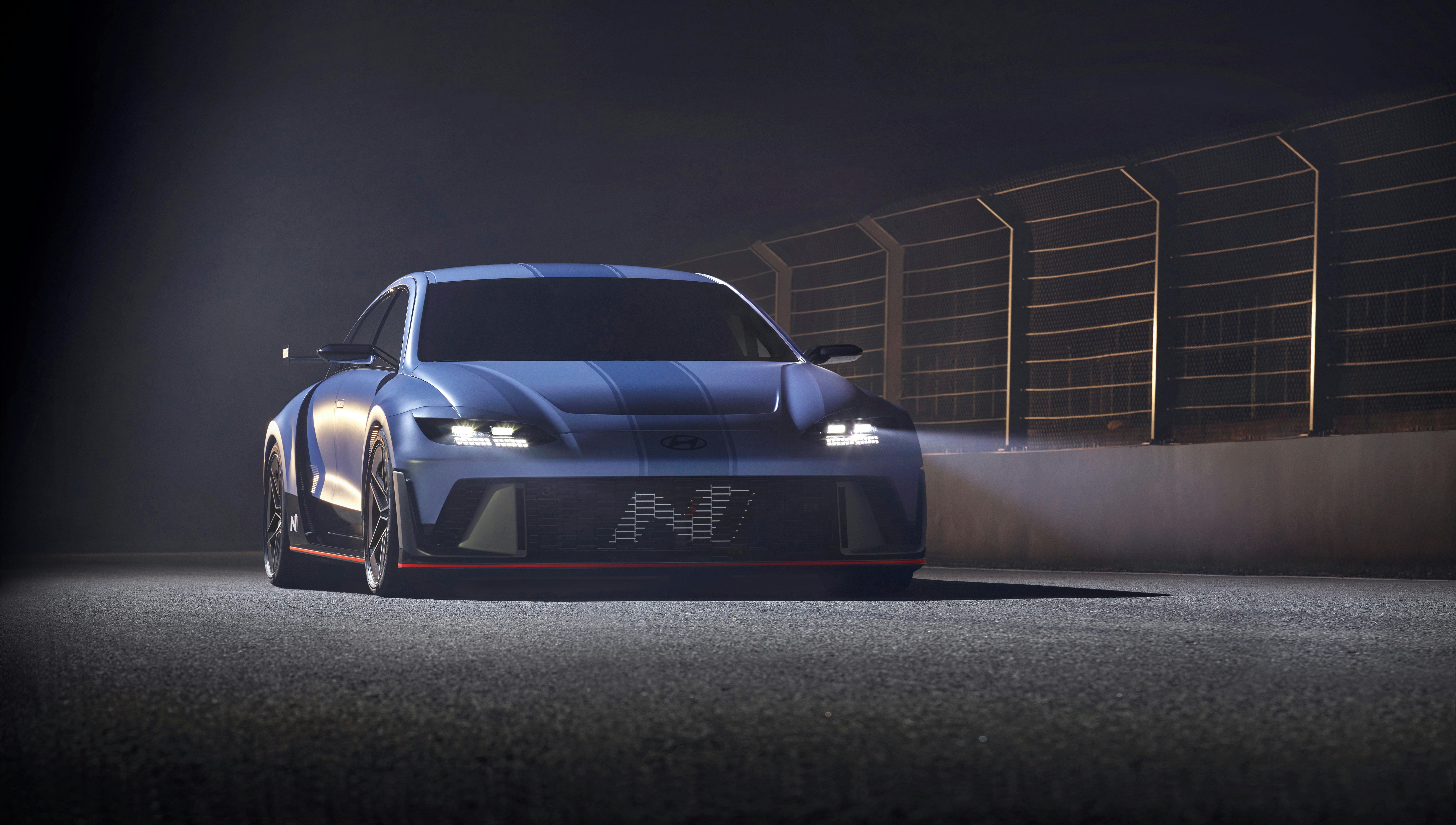 A modern blue sports car parked on an illuminated track at night, showcasing its sleek design.
