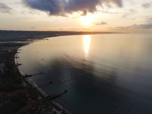 Free Stunning aerial view of sunrise over Pangandaran, Indonesia coastline, capturing the serene sea and horizon. Stock Photo