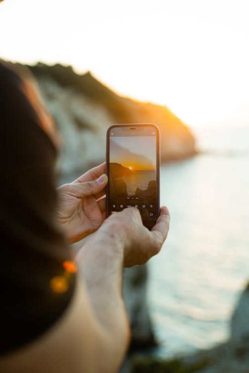 Hands Filming Sunset on Mobile Camera