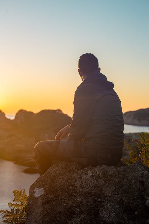 Man Sitting on the Rock during Sunset