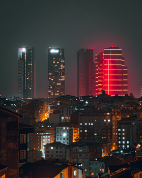 A vibrant city skyline at night, featuring illuminated skyscrapers and urban architecture.