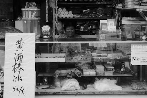 Black and White Photo of Woman Selling in Food Shop