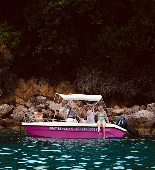 People Riding on White and Pink Boat on Body of Water