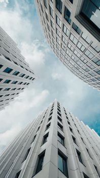 Low-angle view of modern skyscrapers reaching into a cloudy sky, capturing urban elegance and geometric design.