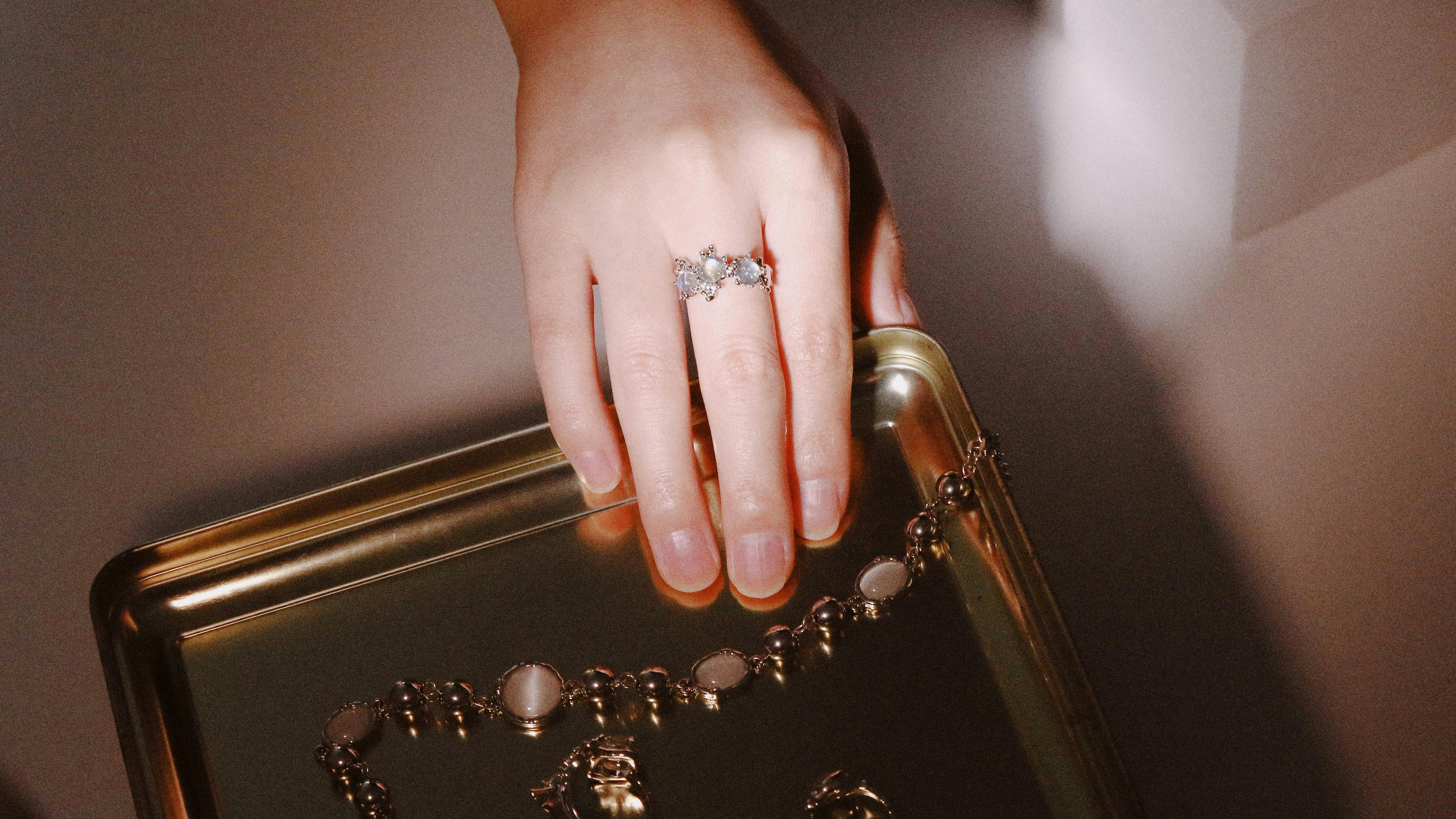 hand of a person wearing a ring on a gold tray