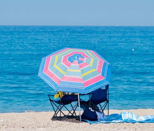 Free Vibrant beach umbrella and chairs on the tranquil shores of Perdika, Greece. Stock Photo