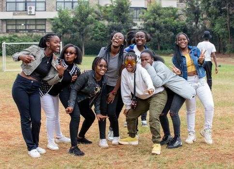 A joyful group of women in casual attire posing outdoors on a grassy field, showcasing friendship and happiness.