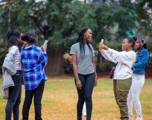 Free A group of friends enjoying a casual day outdoors, capturing moments with smartphones. Stock Photo