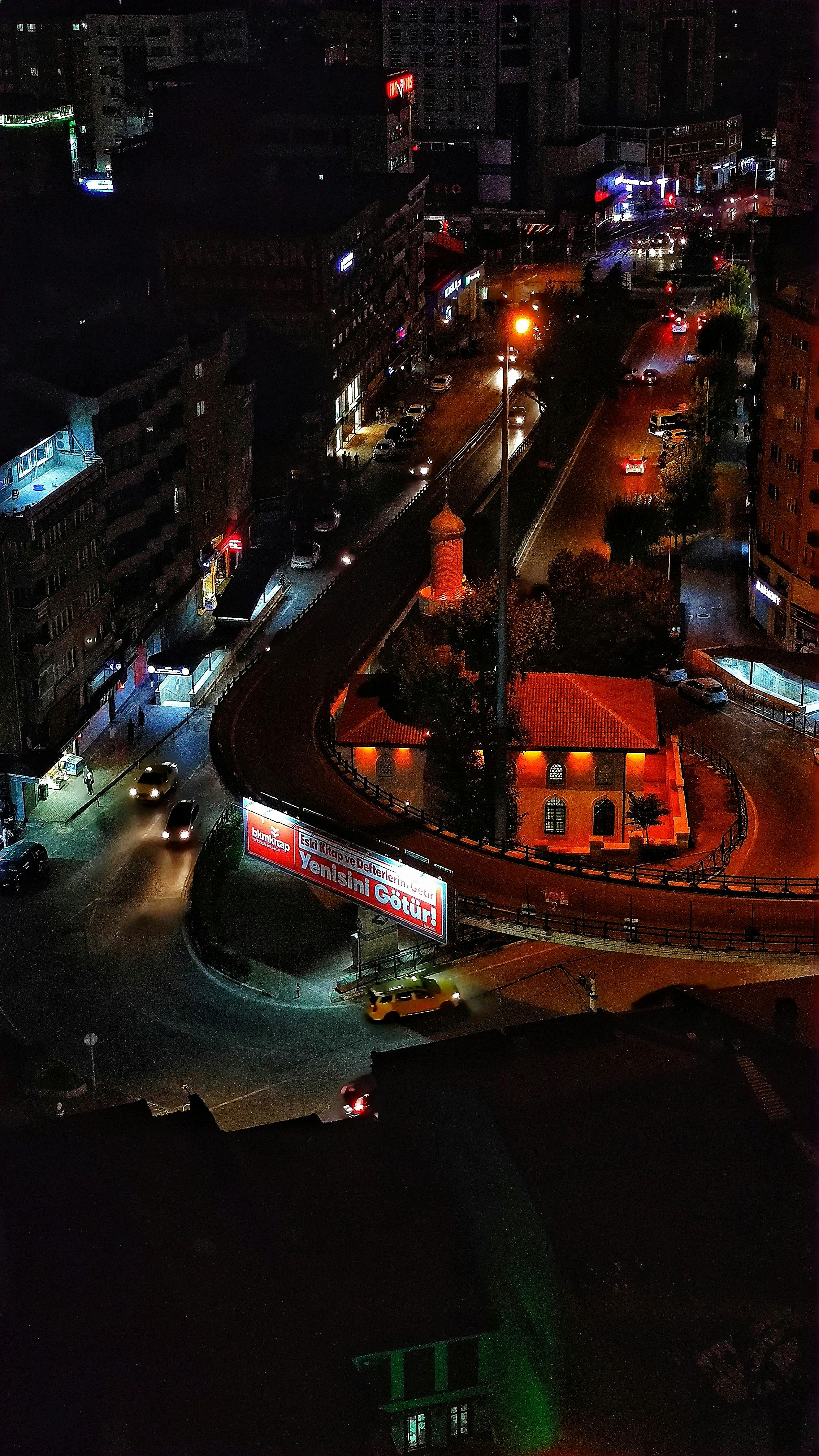 Vivid aerial night view of a bustling urban overpass with illuminated streets, showcasing city life.