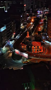 Vivid aerial night view of a bustling urban overpass with illuminated streets, showcasing city life.
