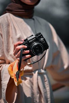 Person holding a vintage Zenit camera outdoors, focusing on photography.