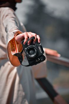 Close-up shot of a hand holding a vintage Zenit camera outdoors, highlighting photography passion.
