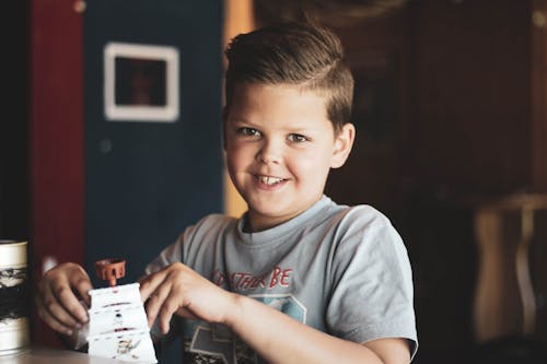 Boy Holding Toy on Top of Table