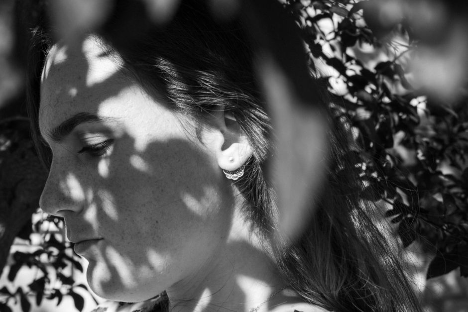 Monochrome side view portrait of woman with shadows, wearing an earring.