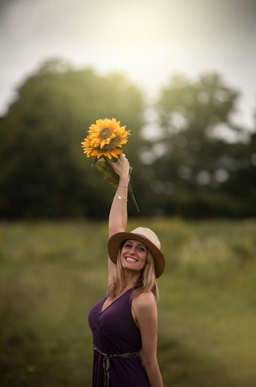 Photo of Smiling Woman Holding Up Bouquet of Sunflowers