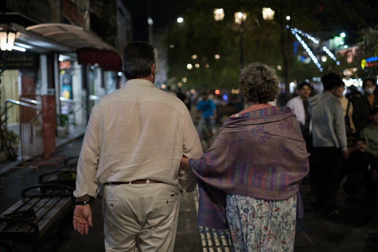 An Elderly Couple Walking On A Sidewalk