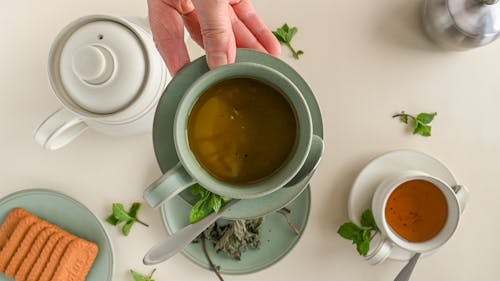 Free A Hand Holding a Saucer with Cup of Coffee Stock Photo