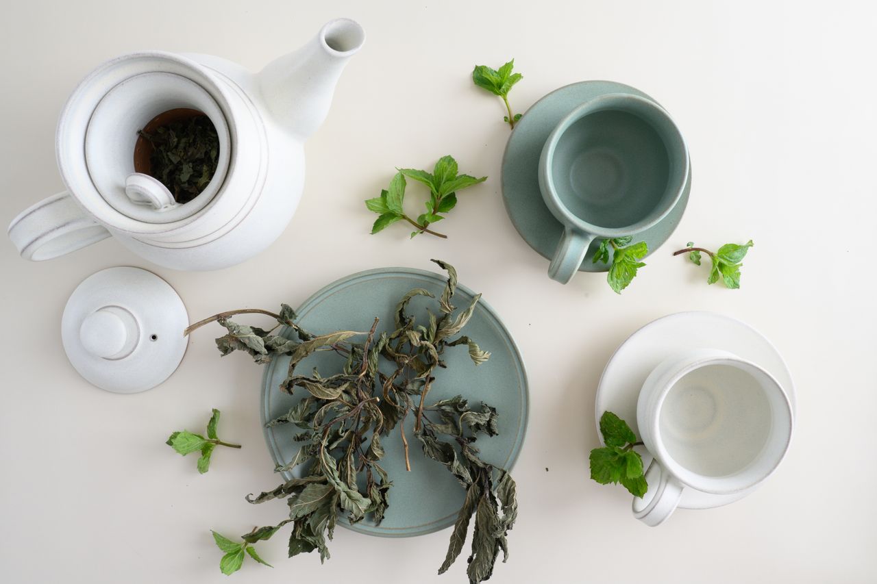 aesthetic top view of a teapot with cups and dried herbal tea leaves o