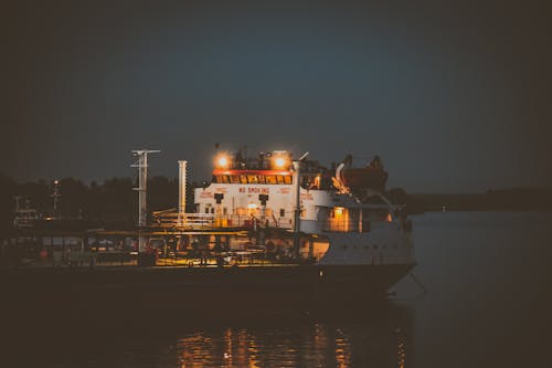 A Cargo Ship Sailing on the Sea Under Night Sky