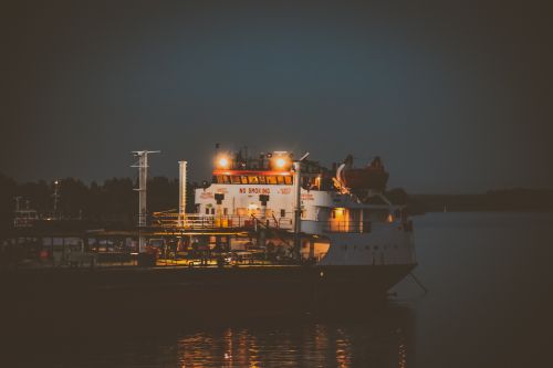 Free A cargo ship docked at night with bright lights illuminating the deck. Stock Photo