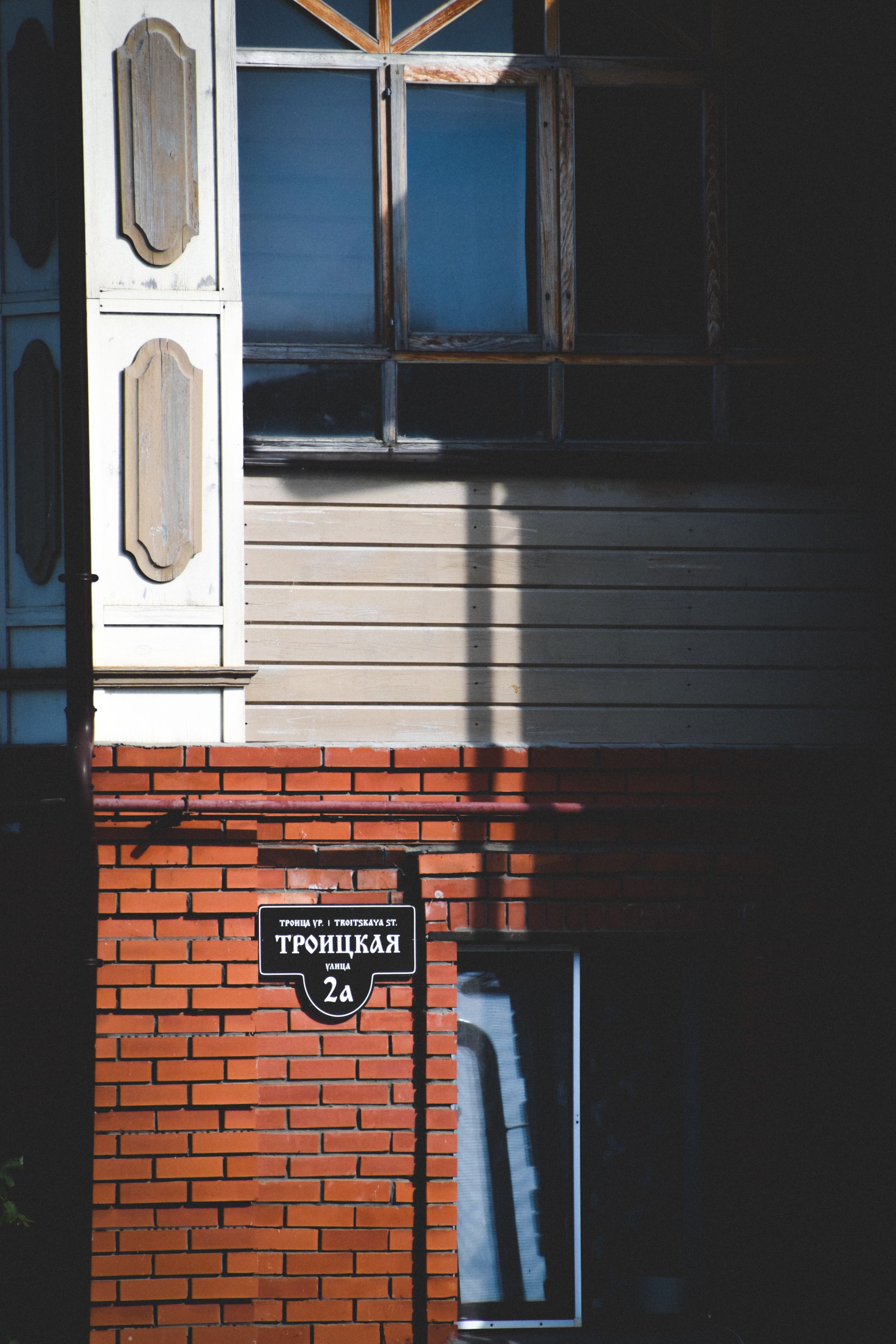 Vertical shot of a brick building exterior with a glass window and a street sign.