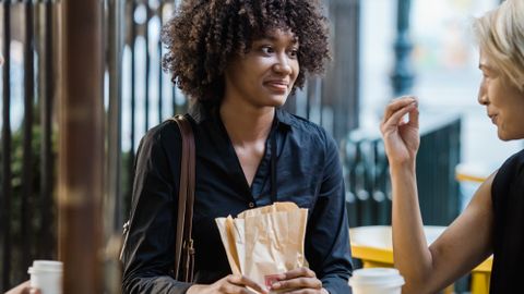 Two women enjoying conversation and coffee at an outdoor café.